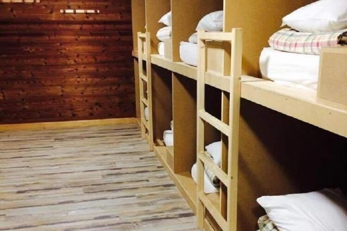 A room with bunk beds, wooden walls, and a sloped ceiling.