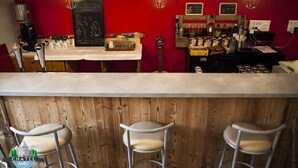 A bar area with a red wall, wooden paneling, and three metal bar stools. - 1861 Châtel Hostel (Chatel)