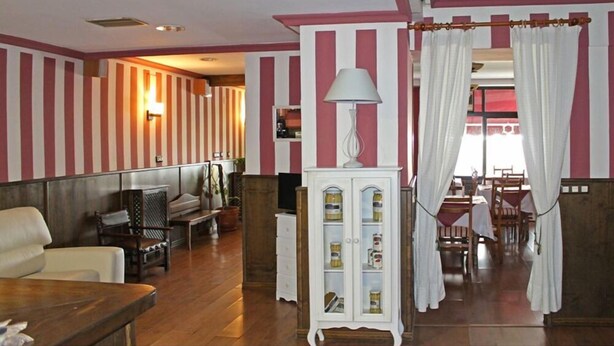 A room with striped walls, a wooden floor, a white cabinet with glass doors, a lamp, and a dining area with chairs and a table. - Hostería Verahouse (Jaraíz de la Vera)