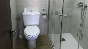 A modern bathroom with a toilet, a glass shower enclosure, and a wooden floor. - Hostería Verahouse (Jaraíz de la Vera)