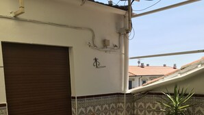 A covered patio area with a table and chairs, a potted plant, and patterned tiles on the walls. - Hostería Verahouse (Jaraíz de la Vera)
