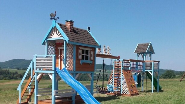 A playground with a slide, climbing wall, and swings. - Grand Panorama (Wisniowa)