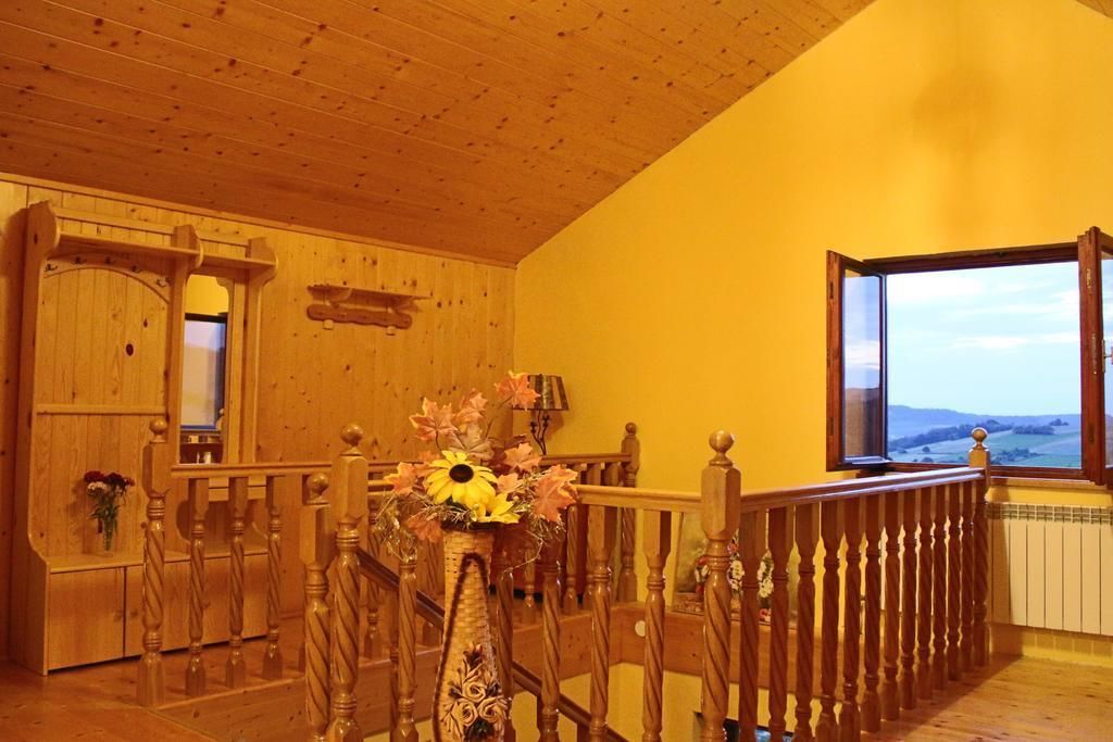 A wooden interior with a staircase, a window with a view, and a vase with flowers.