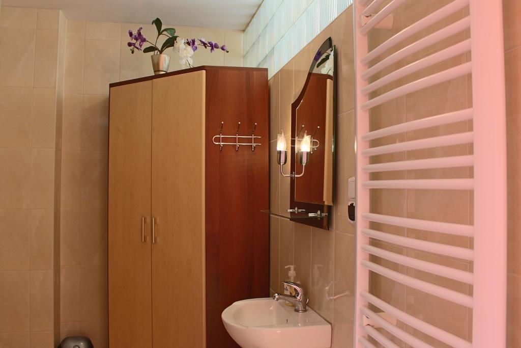 A bathroom with a wooden wardrobe, a mirror, a sink, and a towel rack.