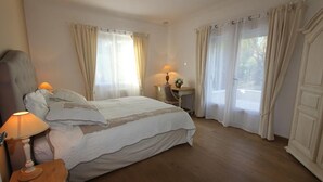 Un dormitorio con cama, mesita de noche, lámpara y cortinas.