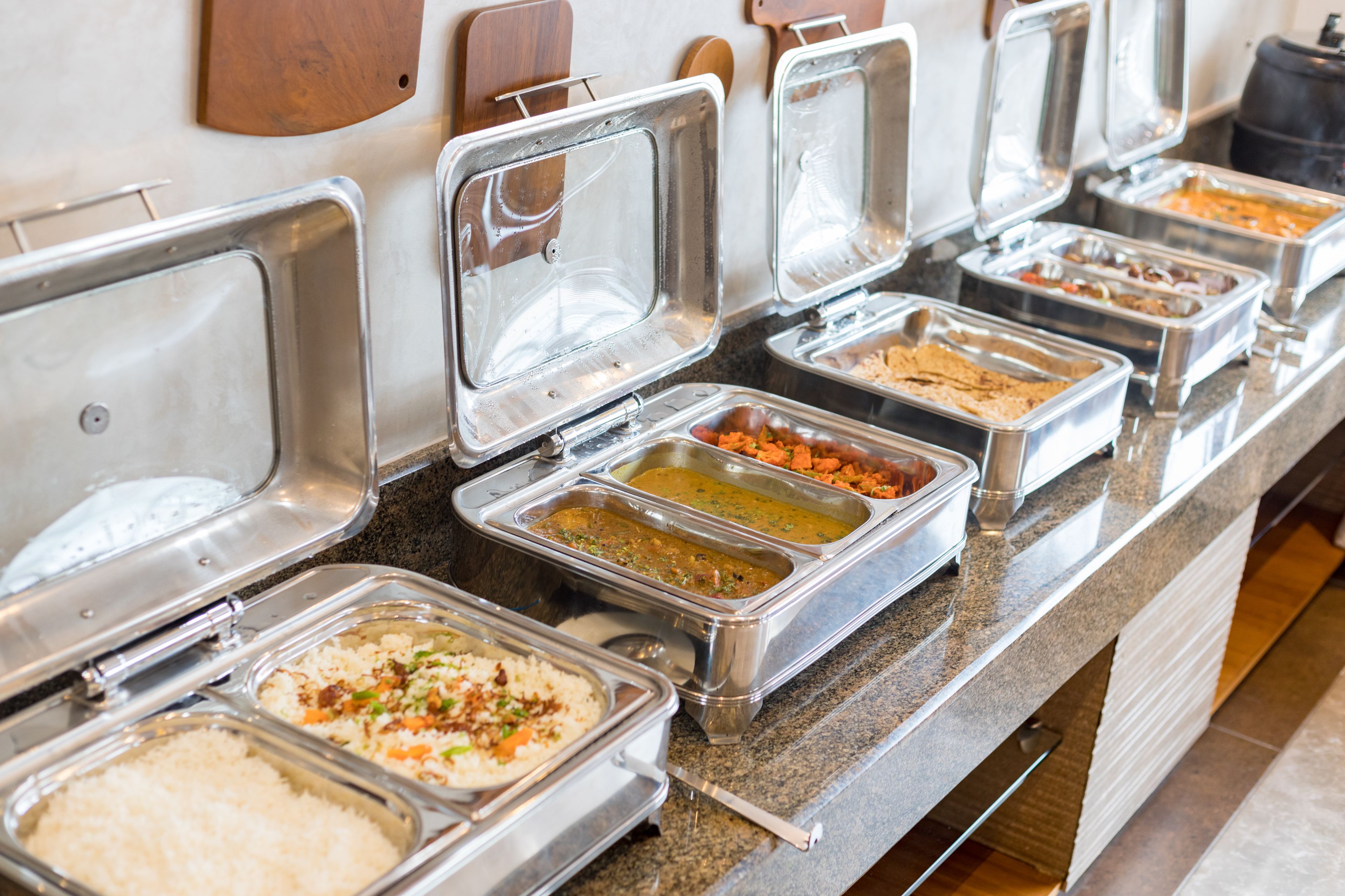 A buffet line with various food options in metal containers.
