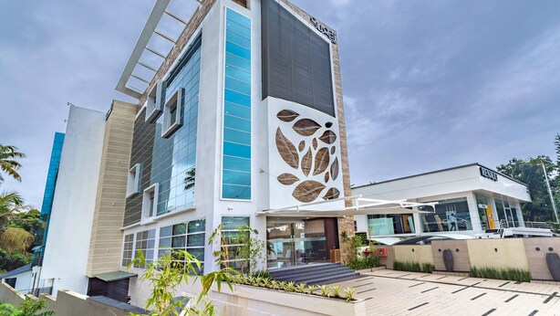 Un hotel moderno con un diseño vertical llamativo, ventanas amplias y un motivo decorativo de hojas en la fachada.