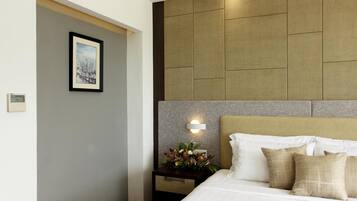 A hotel room with a bed, a nightstand with a flower arrangement, and a framed picture on the wall.
