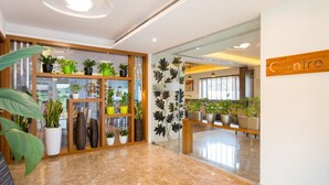 Un lobby moderno con un panel de vidrio, plantas en macetas y un letrero que dice "Cilantro".