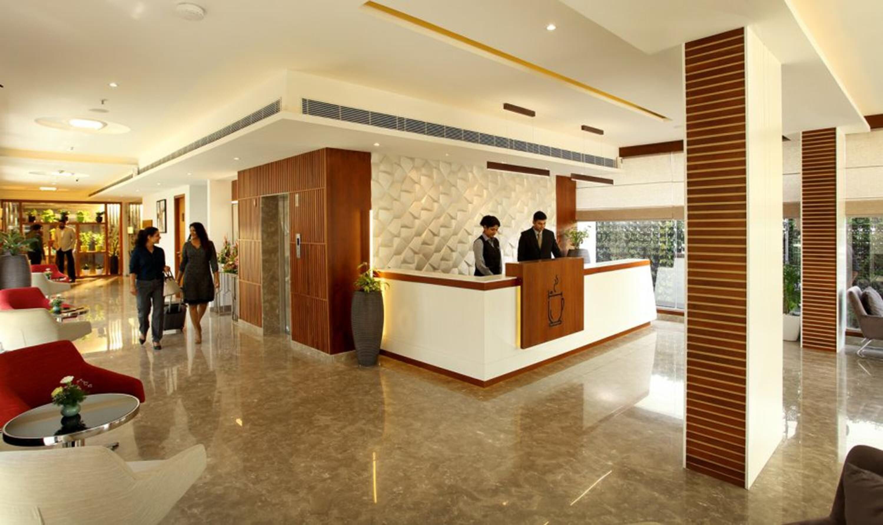 Eine moderne Hotelhalle mit einer Rezeption, Sitzbereichen und einem großen Fenster mit Blick ins Freie.