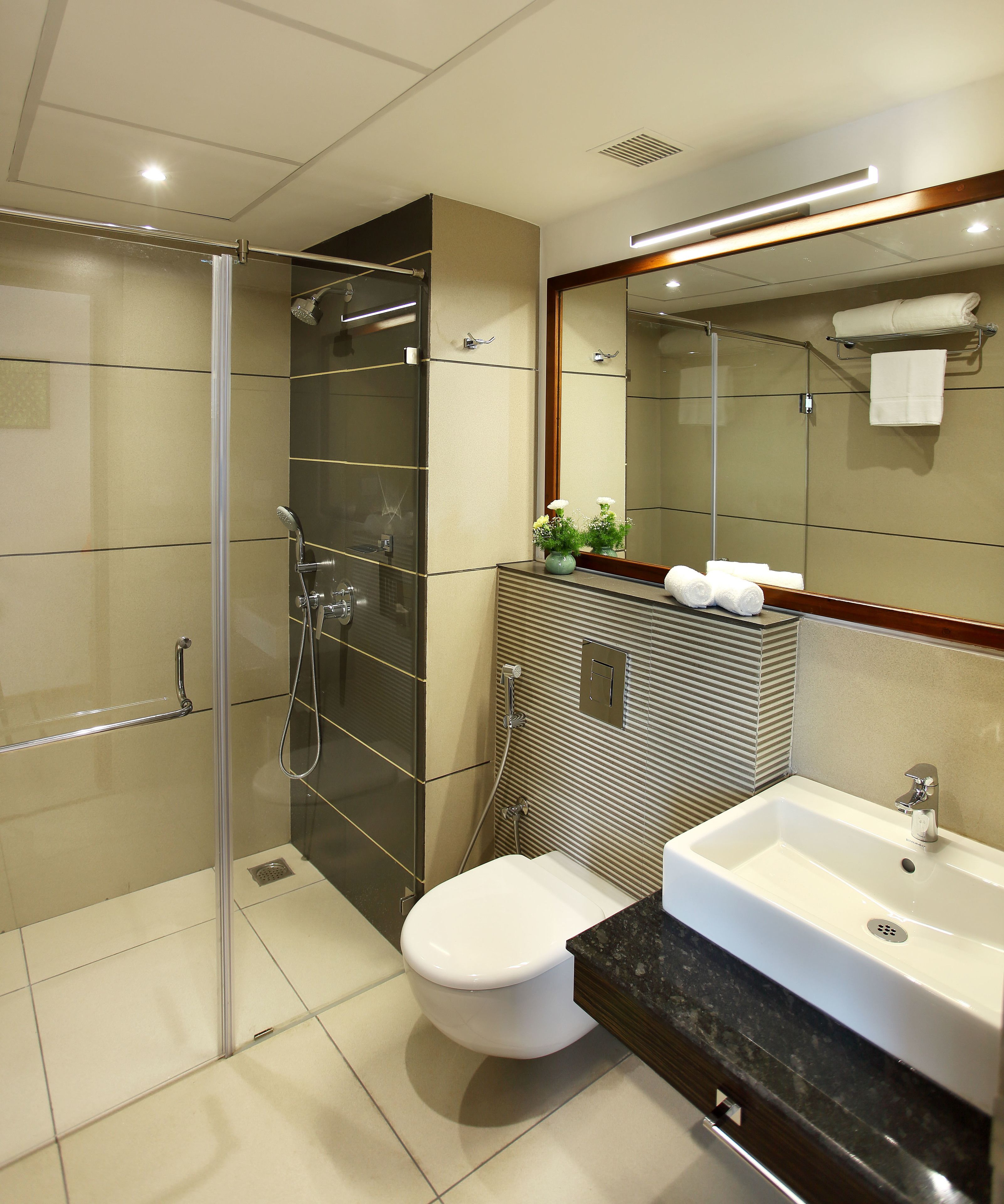 Un baño moderno con ducha de vidrio, inodoro blanco y lavamanos con encimera de mármol.