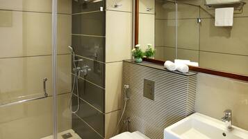 Un baño moderno con ducha de vidrio, inodoro blanco y lavamanos con encimera de mármol.