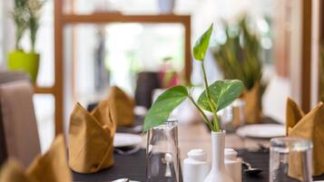 Une table à manger dressée avec de la vaisselle transparente, des vases blancs et des serviettes marron.