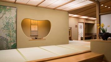 A traditional Japanese interior with tatami flooring, a shoji screen, and a calligraphy scroll.