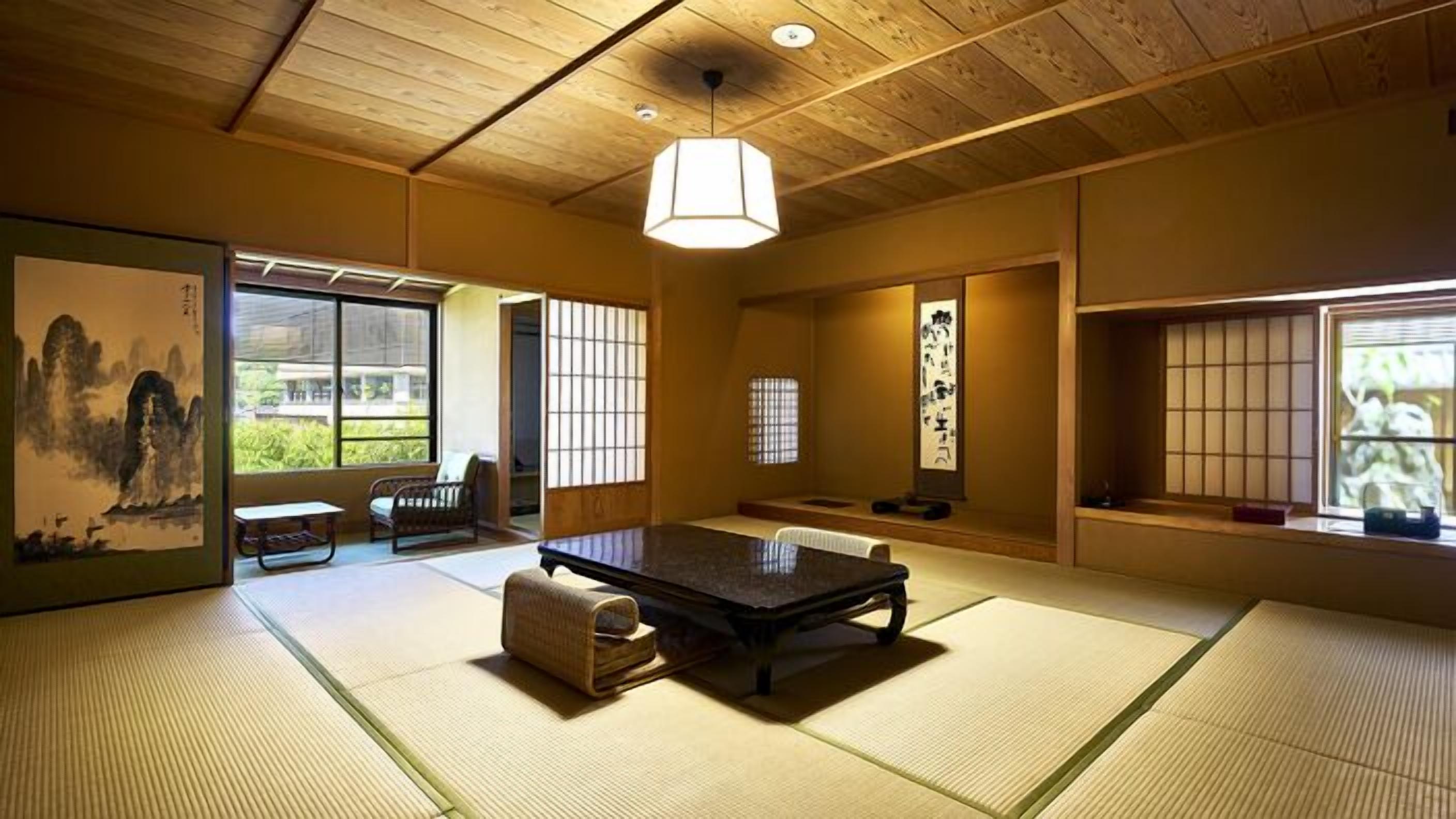 A traditional Japanese room with tatami flooring, a low table, a hanging light fixture, sliding doors, and a view of greenery outside.