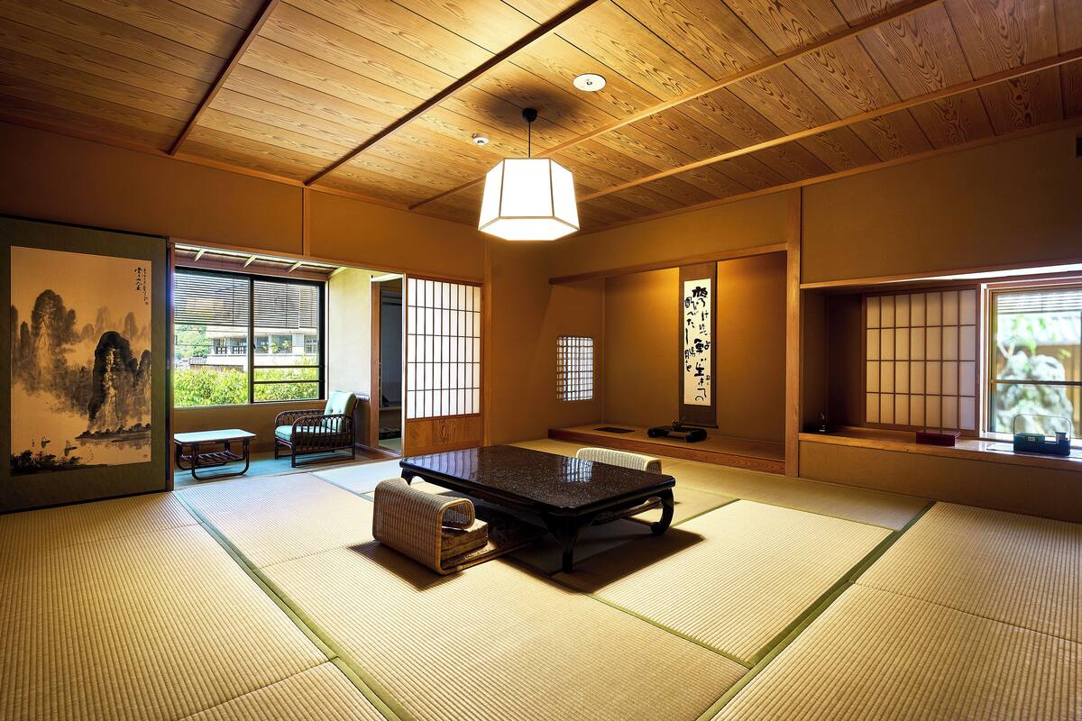 Um quarto japonês tradicional com piso de tatame, uma mesa baixa e portas deslizantes.