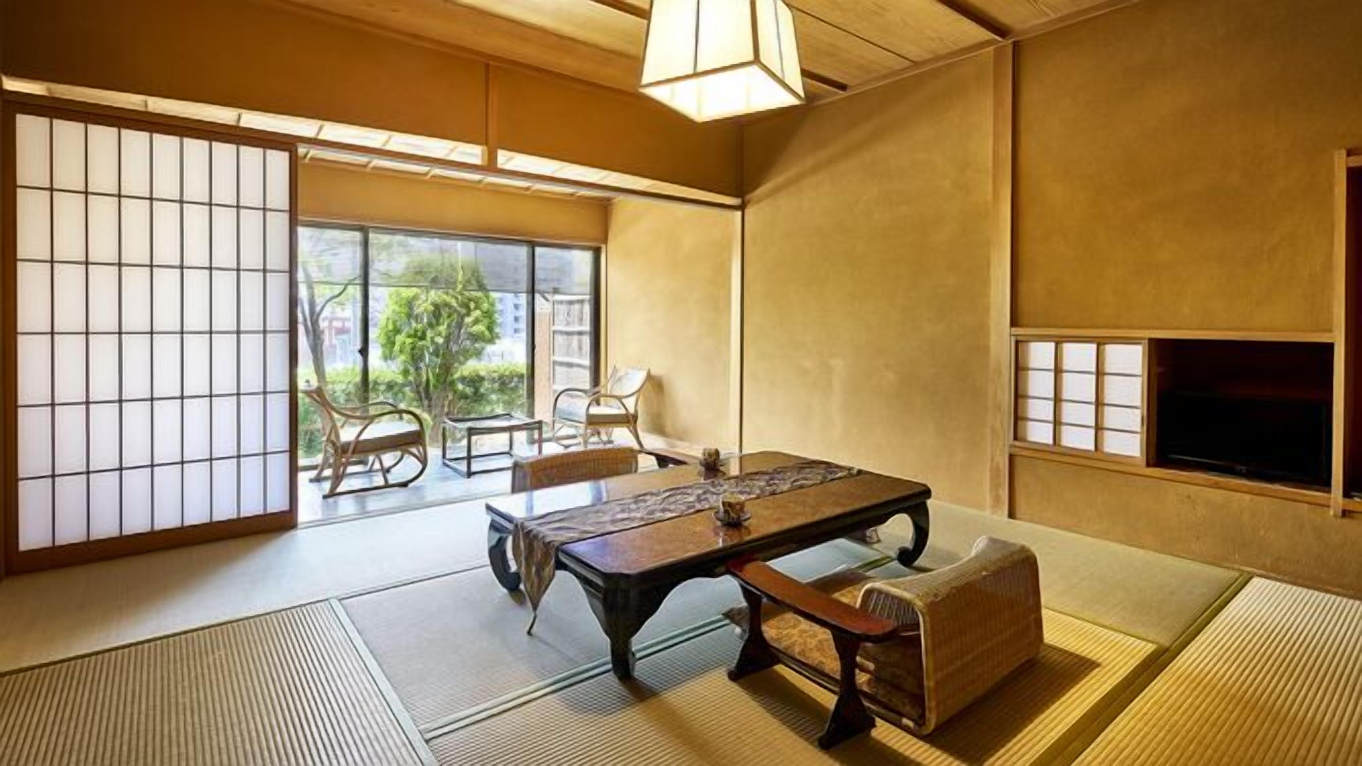 A traditional Japanese room with tatami flooring, a low table, and sliding doors.