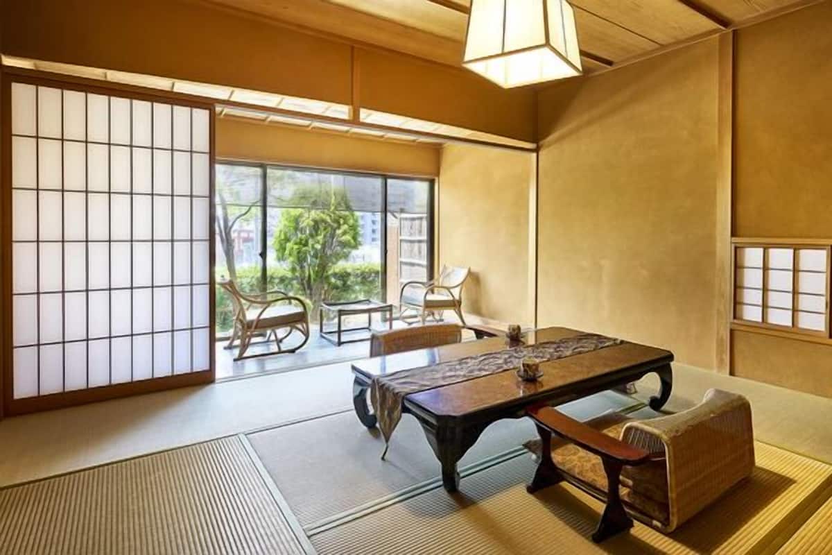 Ein traditioneller japanischer Raum mit Tatami-Bodenbelag, einem niedrigen Tisch und Schiebetüren.