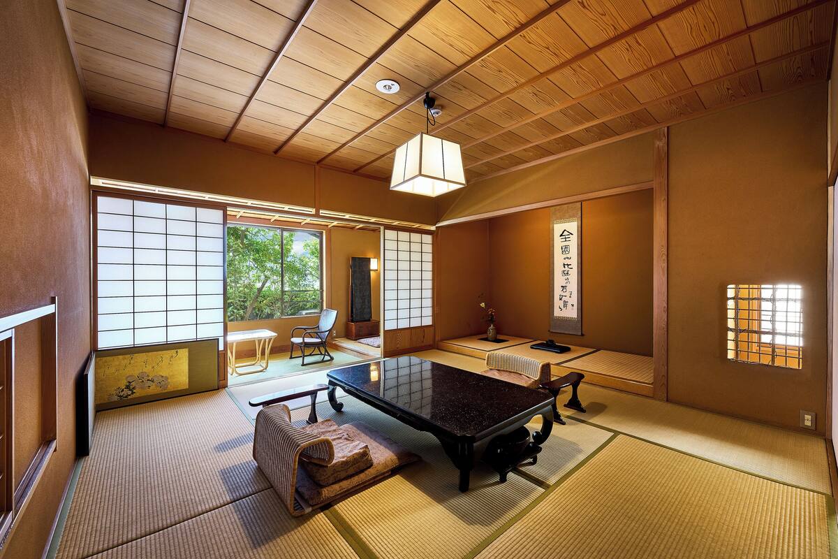 Um quarto japonês tradicional com tatames, uma mesa baixa e portas deslizantes.
