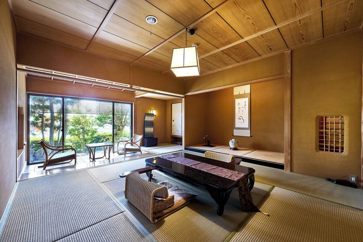 Um quarto japonês tradicional com tatames, uma mesa baixa e portas deslizantes para um jardim.