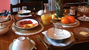 Una mesa de comedor dispuesta con platos, vasos y una variedad de frutas y pasteles.