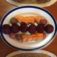 Un piatto di cantalupo a fette e uva su una piastra bianca con bordo blu.
