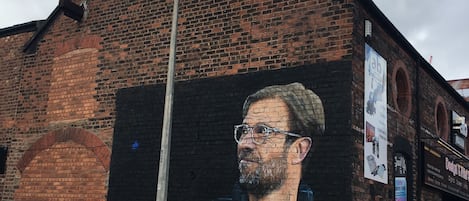 A mural of a man on a brick building with a street lamp in front.
