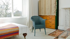 Una habitación con una cama, una silla, un aparador y una ventana.