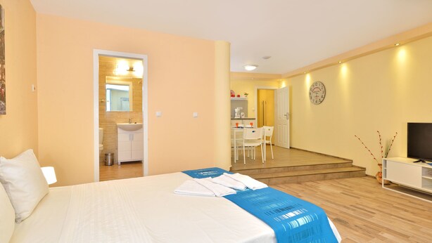 A hotel room with a bed, a desk, a chair, a TV, and a bathroom visible through an open door. - Central Studio 2 (Burgas)