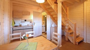 Un interior de madera con comedor, cocina y escalera.