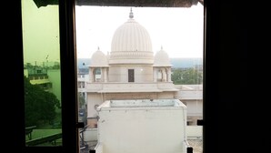 A view of a white building with a large dome and smaller domes, seen through a window with a green frame. - The Metropolis Guest House Near RK Ashram Metro Station (New Delhi)