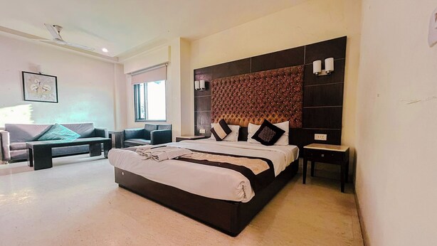 A modern bedroom with a large bed, a sofa, and a small table. - The Metropolis Guest House Near RK Ashram Metro Station (New Delhi)