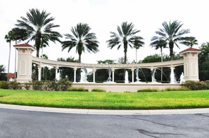 Une structure blanche en forme d’arche, sur laquelle on peut lire l’inscription « Emerald Island », est entourée de palmiers et d’une pelouse bien entretenue.
