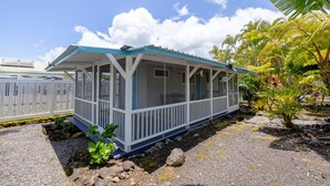 A small, single-story building with a covered porch and a fenced area. - Cozy Tropical Retreat Guest House with AC (Hilo)