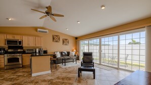 A spacious kitchen with modern appliances, a dining area with a large table, and a balcony with a view. - Cozy Tropical Retreat Guest House with AC (Hilo)