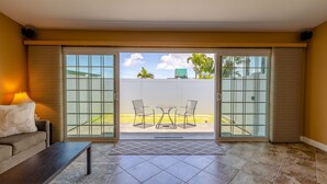 A room with a sliding glass door leading to a patio with a table and chairs. - Cozy Tropical Retreat Guest House with AC (Hilo)