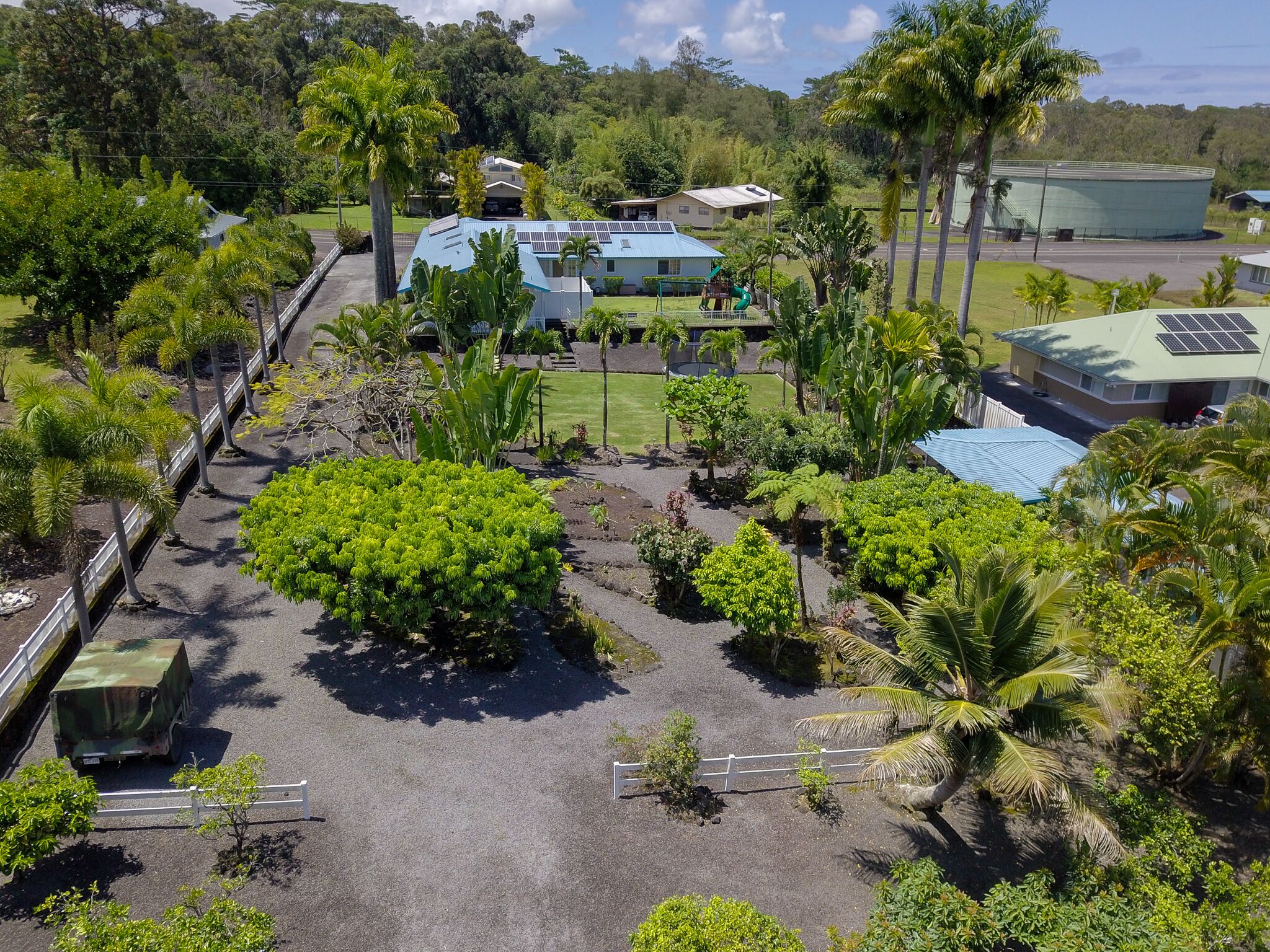 Een tropisch resort met een groot centraal gebouw, omringd door weelderige begroeiing en palmbomen.