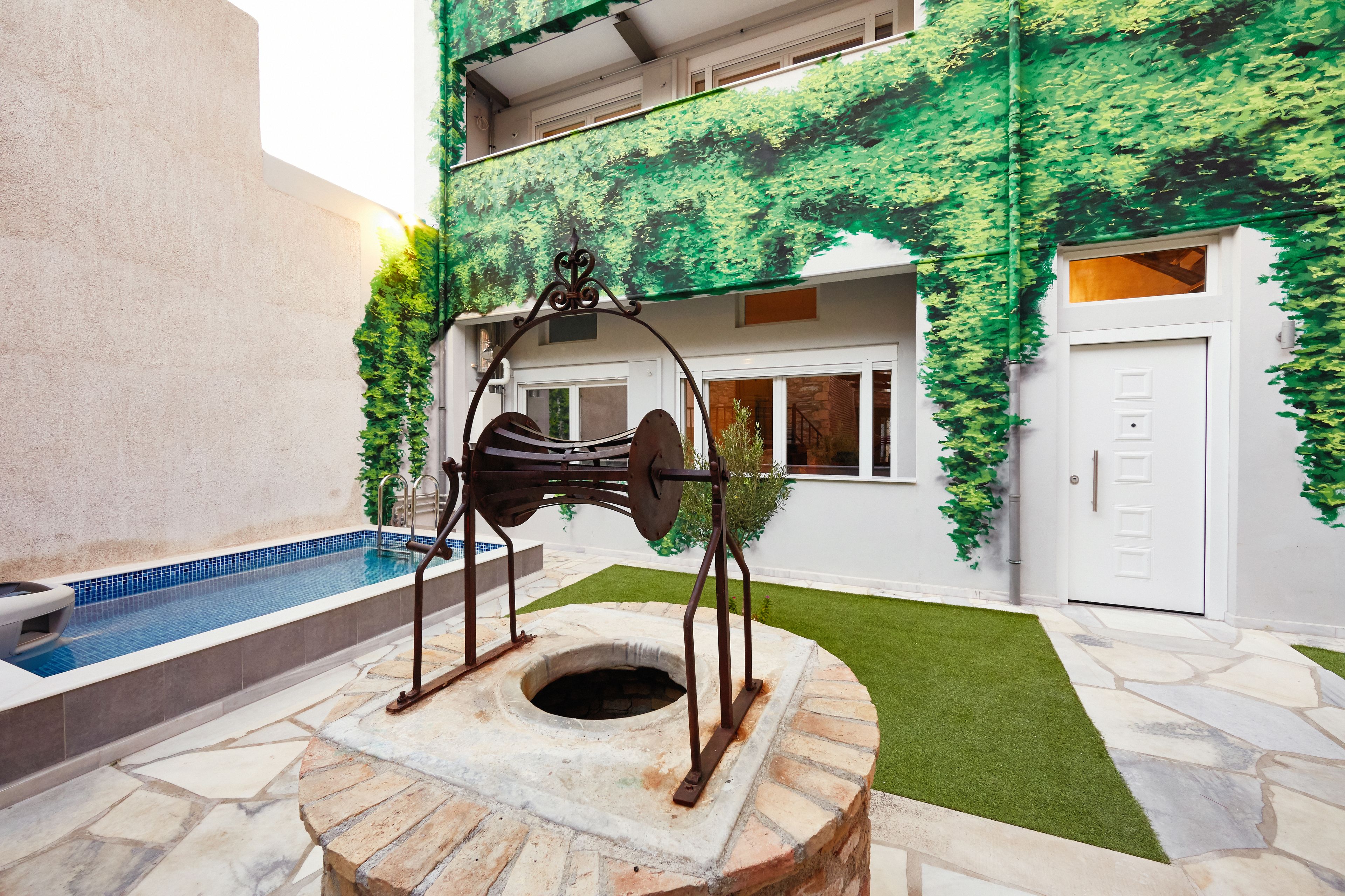 A courtyard with a stone fountain, a swimming pool, and a building with green ivy.