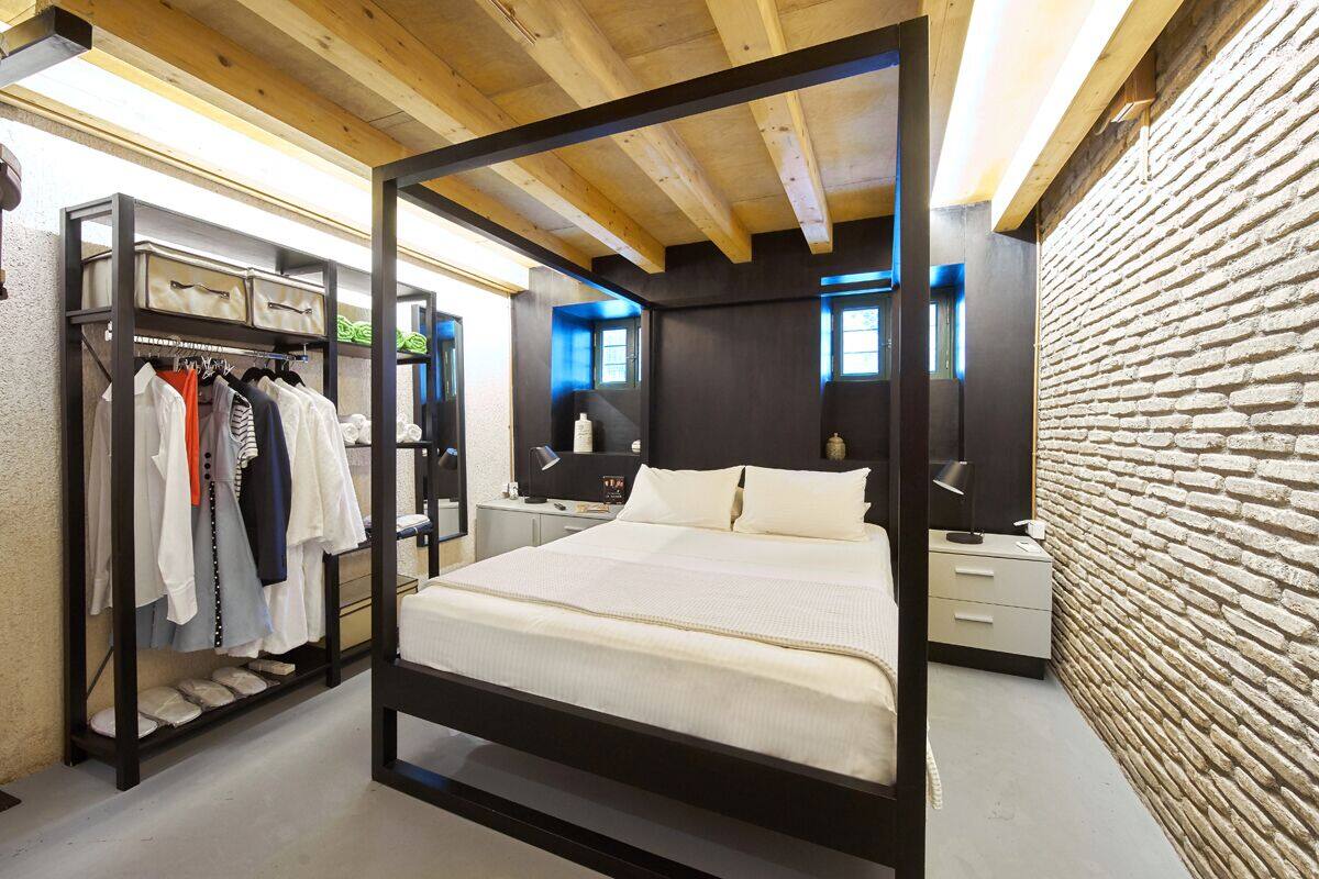Um quarto moderno com cama de dossel, guarda-roupa e parede de tijolos.