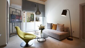 En moderne stue med en sofa, en gul stol, et sofabord, en gulvlampe og et fjernsyn monteret på væggen.