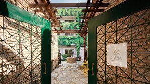 En gårdsplads med stenbelægning, en pergola og et skilt for Athenian Residences.