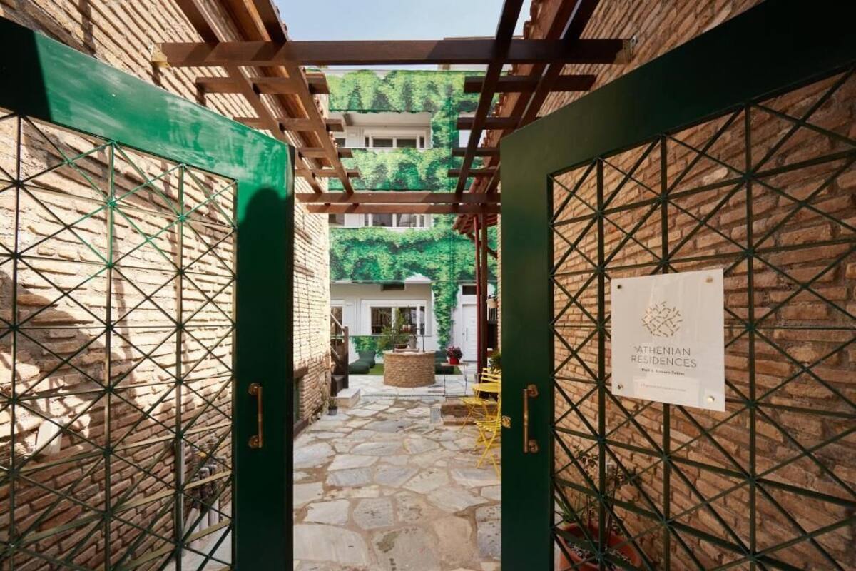 Um pátio com piso de pedra, uma pérgula e uma placa indicando Athenian Residences.