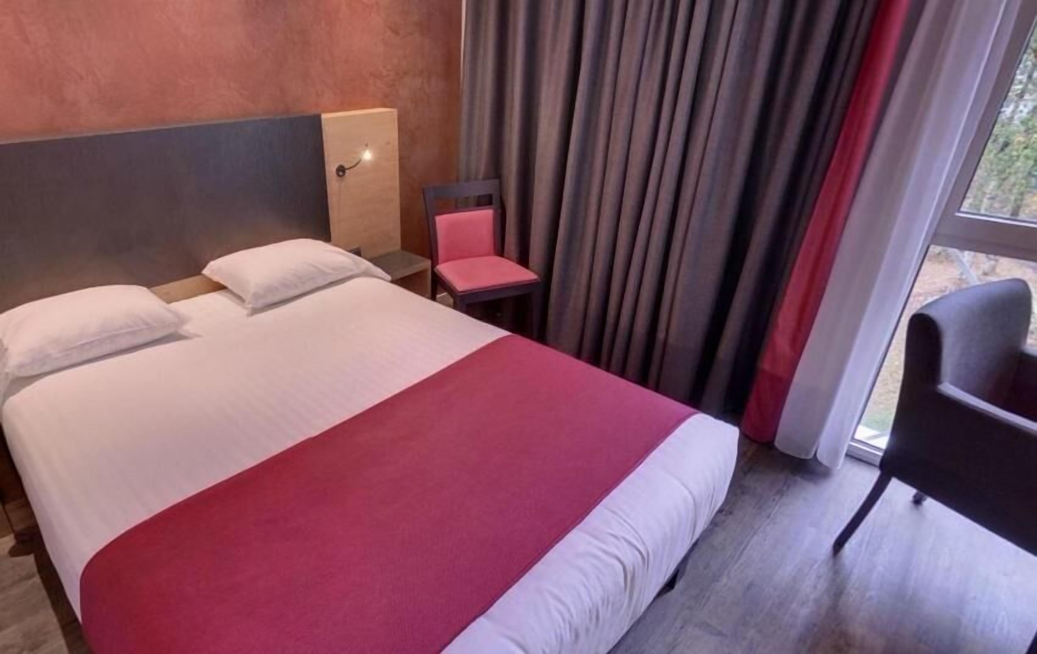 Une chambre d’hôtel avec un grand lit, une table de chevet, une chaise et une vue par la fenêtre.