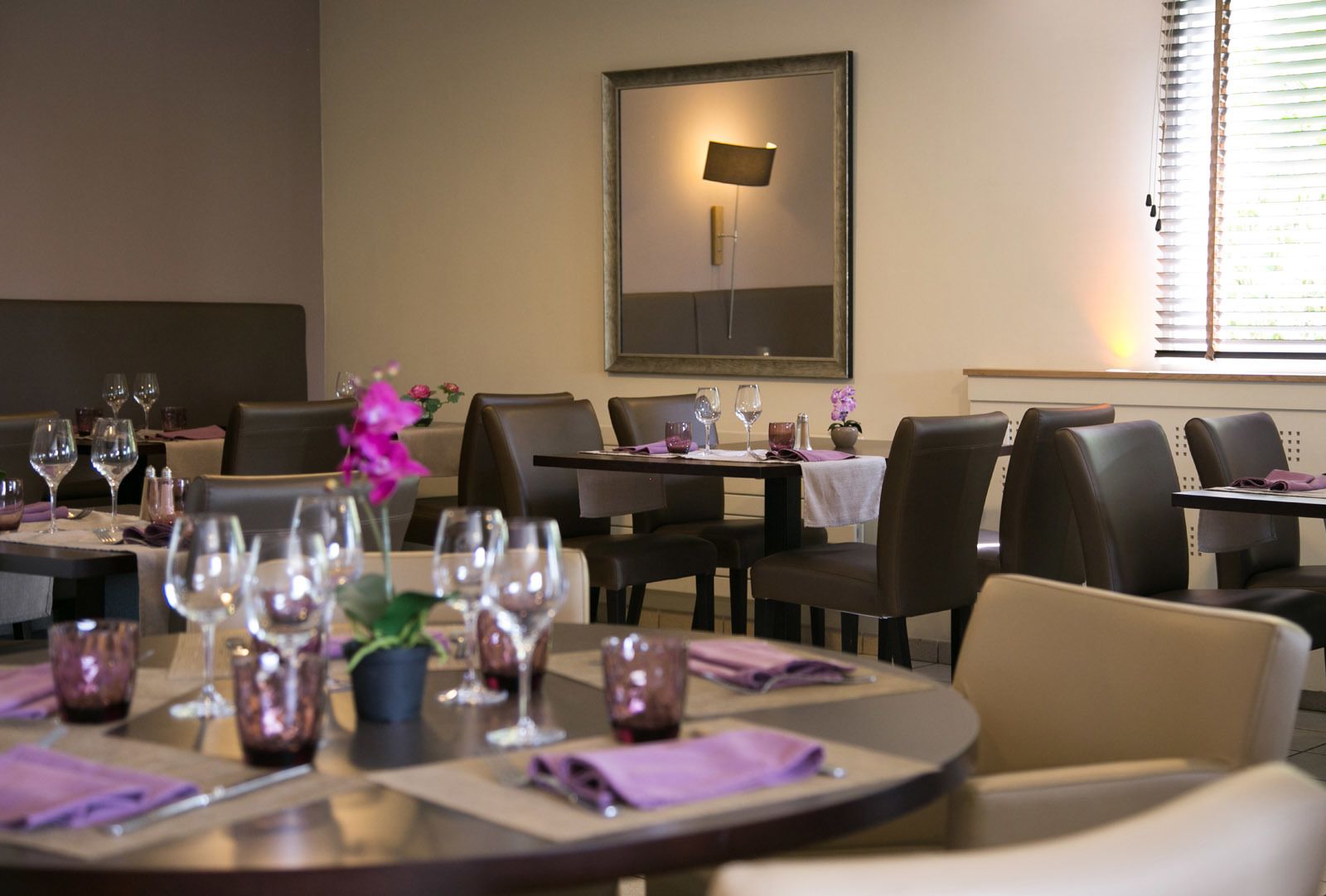 A dining area with tables set for a meal, chairs, and a wall-mounted light fixture.