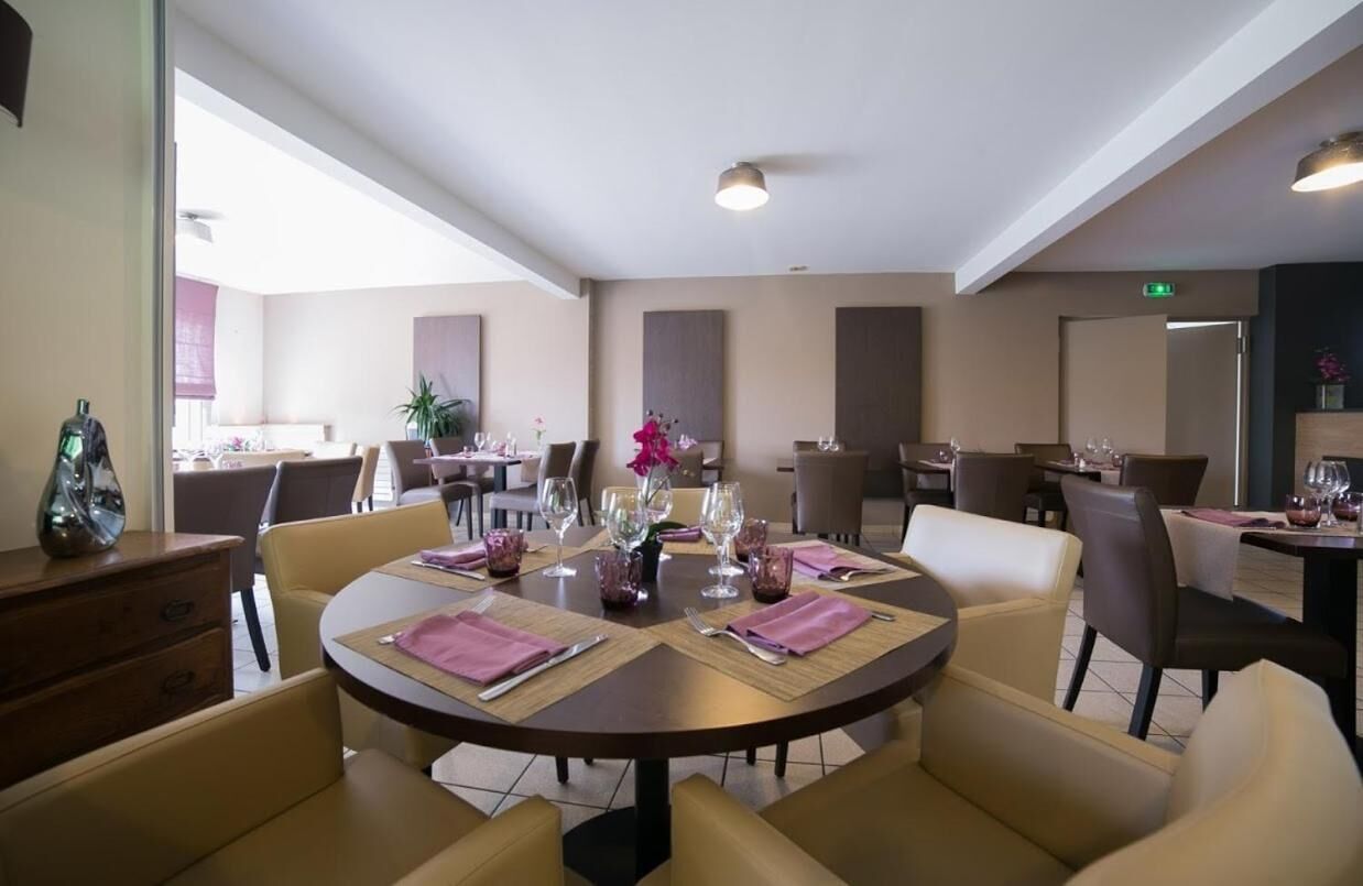 Un espace repas avec des tables rondes, des chaises et une composition florale centrale.