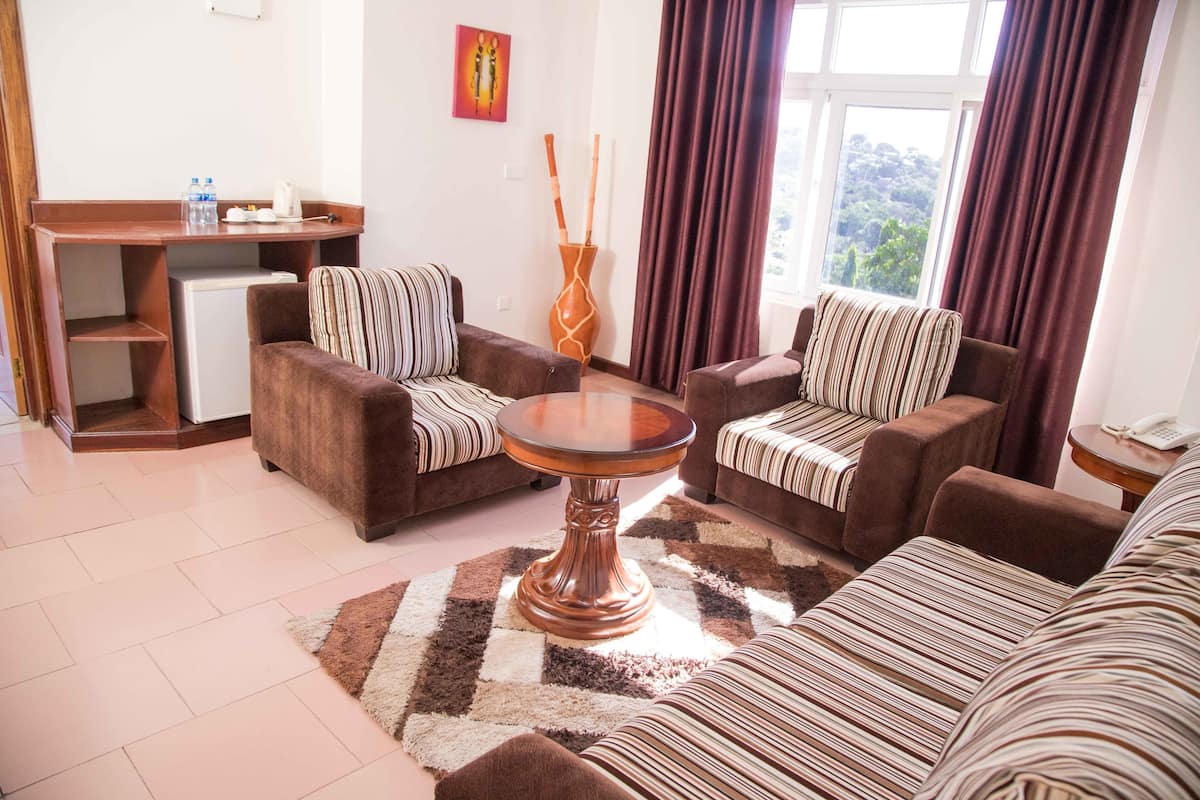 A living room with two sofas, a coffee table, a small table with a vase, and a view of the outdoors through a window.