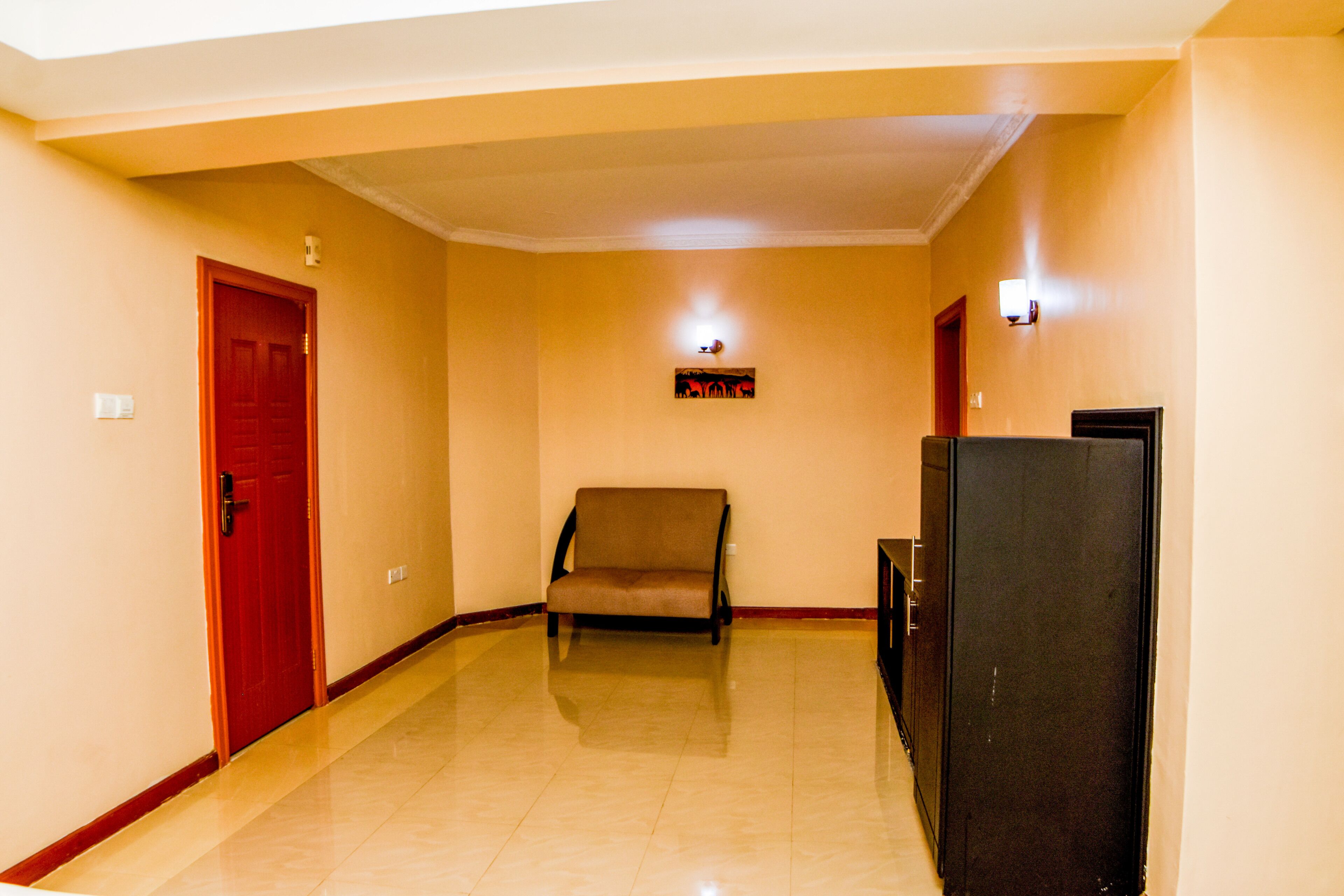 A hallway with a red door, a brown sofa, and a black cabinet.
