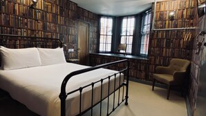 A bedroom with a bed, a chair, a desk, and bookshelves. - The Black Hole (Winchester)