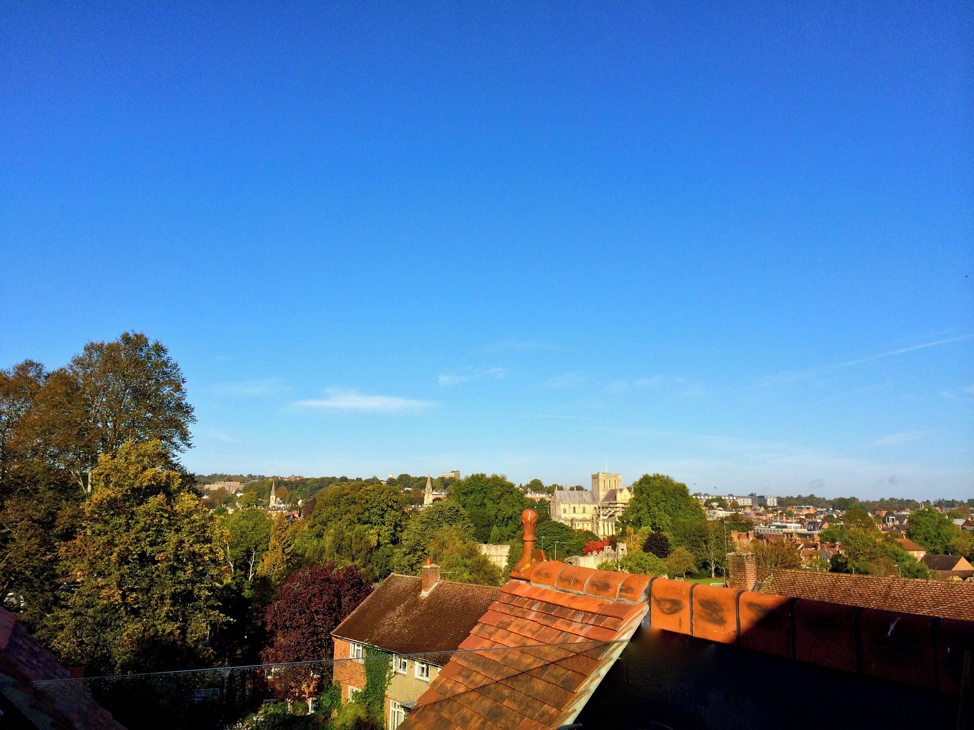 Vista de un pueblo con una torre de iglesia destacada, rodeado de árboles y edificios residenciales.