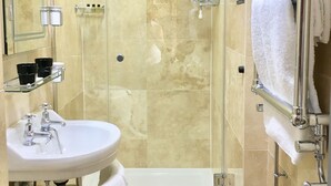 A modern bathroom with a glass-enclosed shower, a white sink, and a glass shelf with toiletries. - The Black Hole (Winchester)